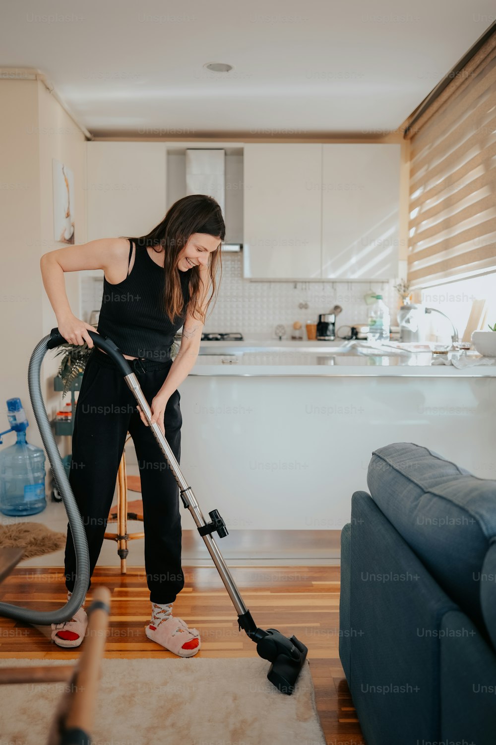 Una mujer está limpiando el piso con una aspiradora