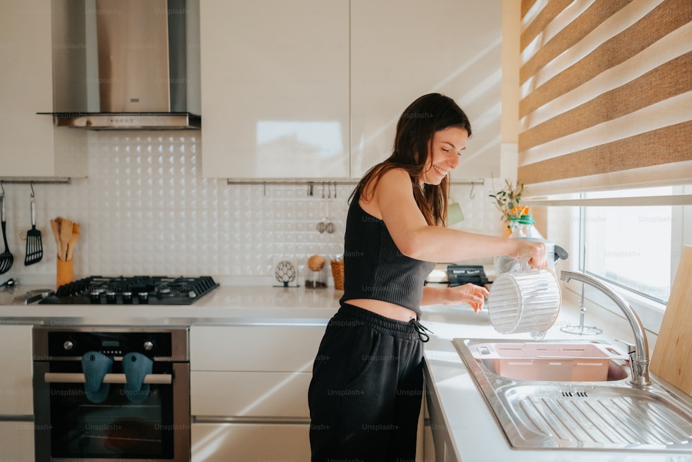a woman in a black top is washing dishes in a kitchen