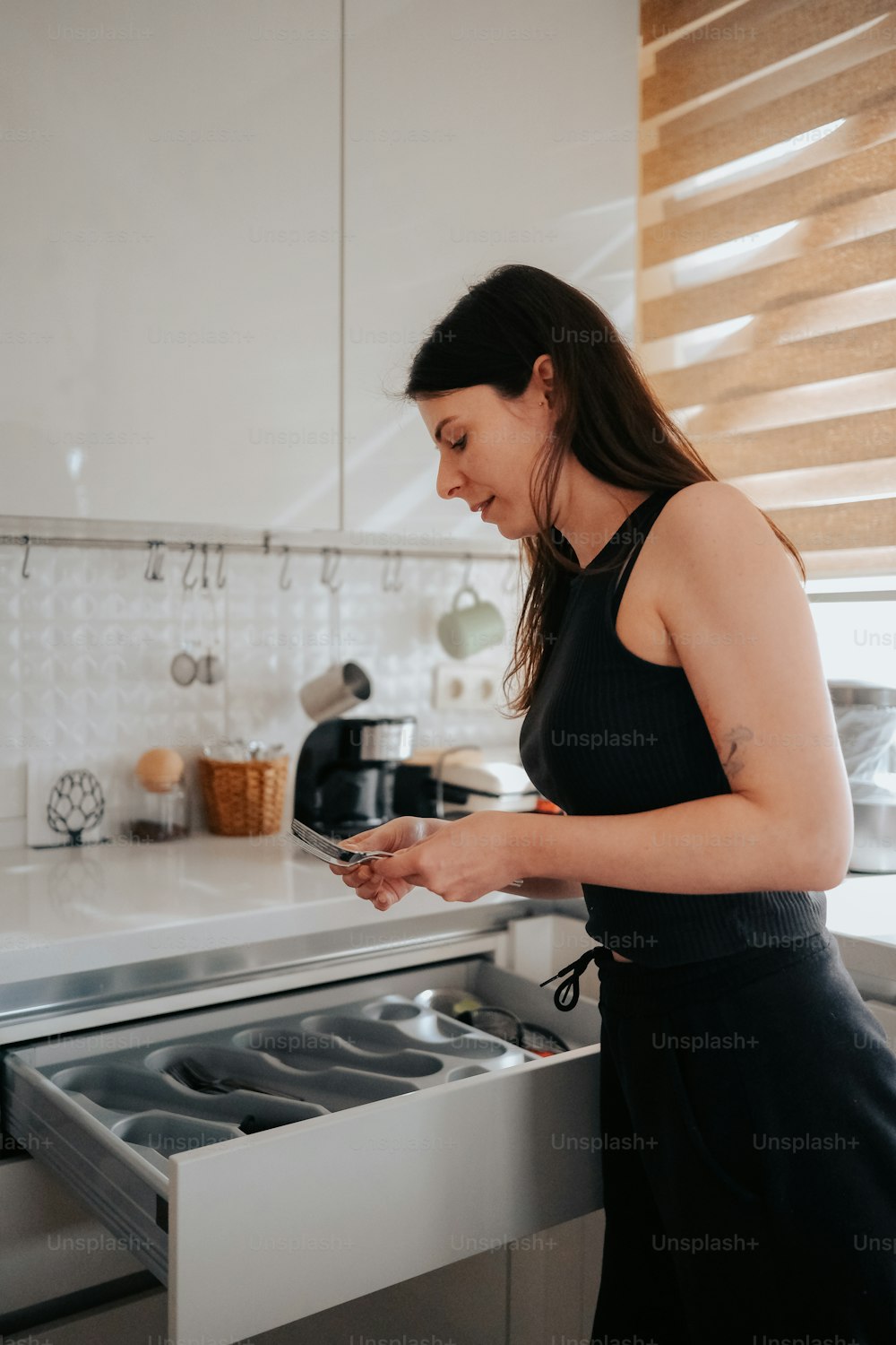 a woman standing in a kitchen looking at a cell phone