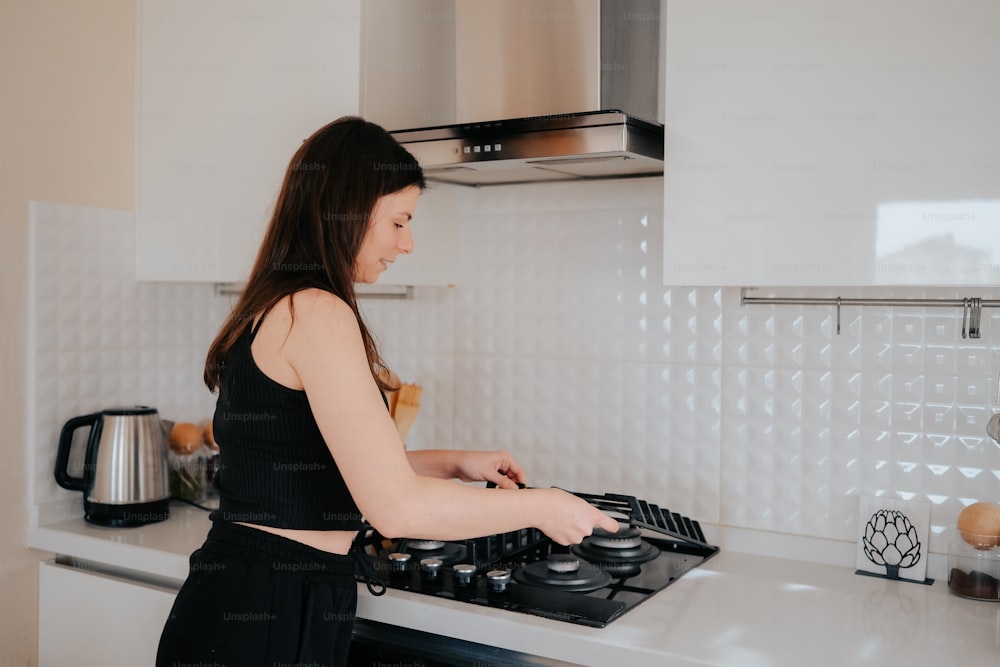 a woman in a black top is cooking on a stove