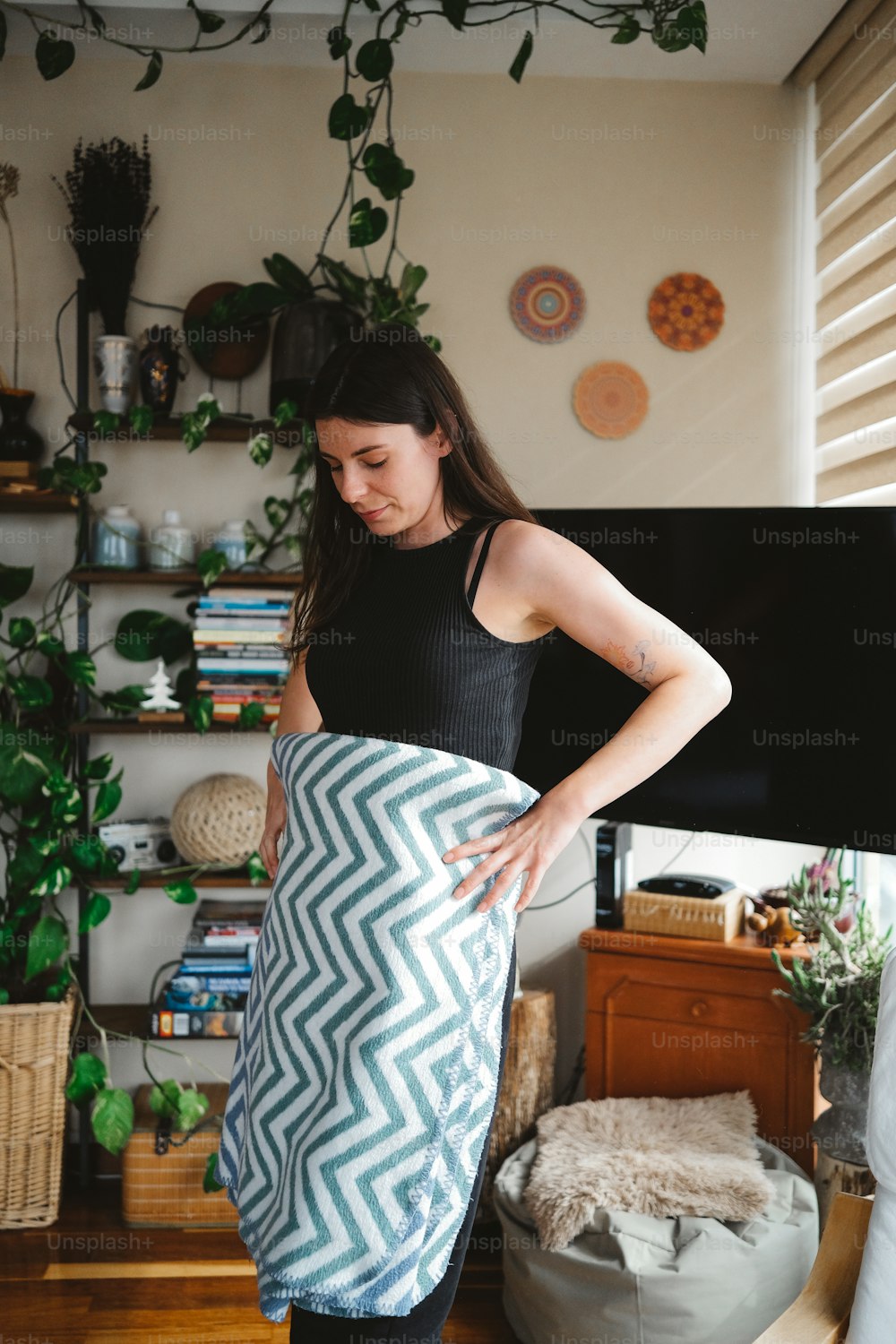 a woman standing in a living room holding a blanket