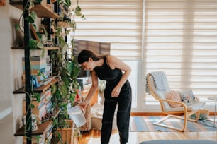 植物でいっぱいの本棚の前に立つ女性