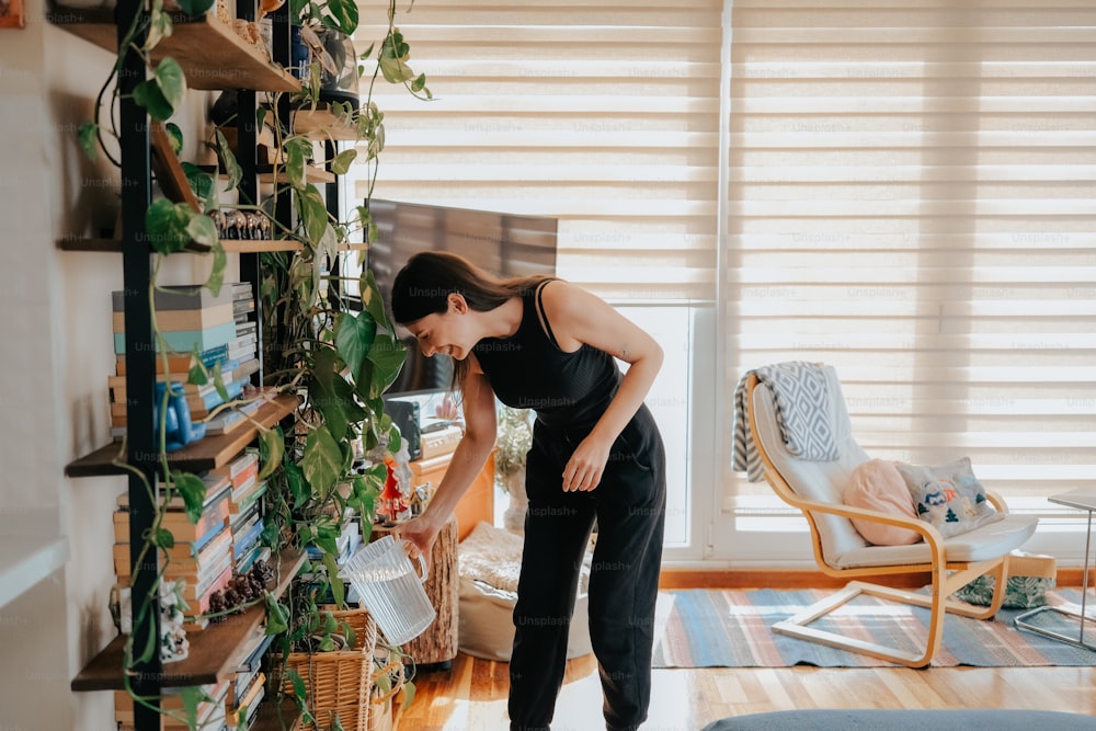 a woman standing in front of a bookshelf filled with plants