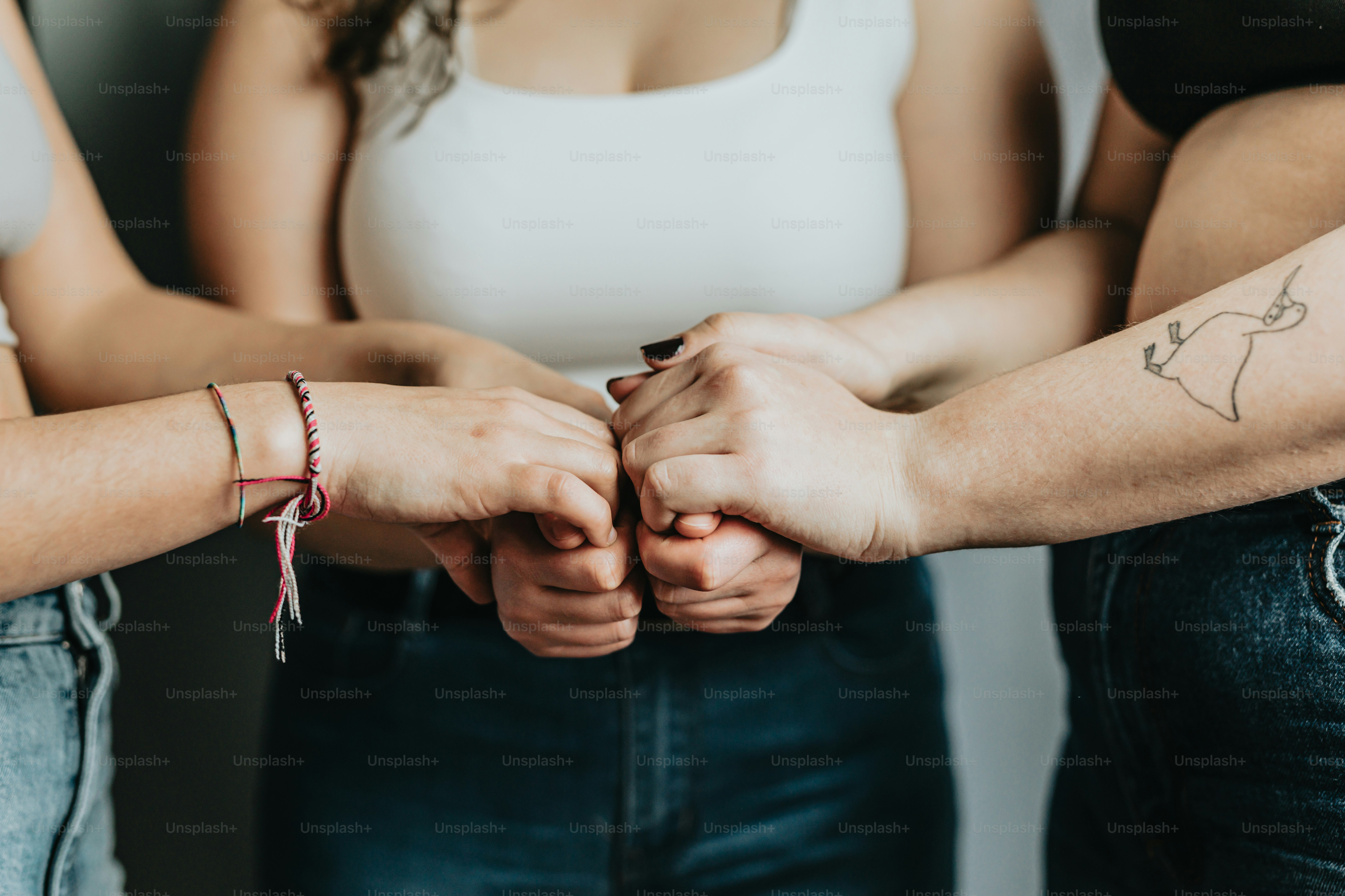 Eine Gruppe von Menschen, die Händchen halten mit Tätowierungen auf ihren Armen