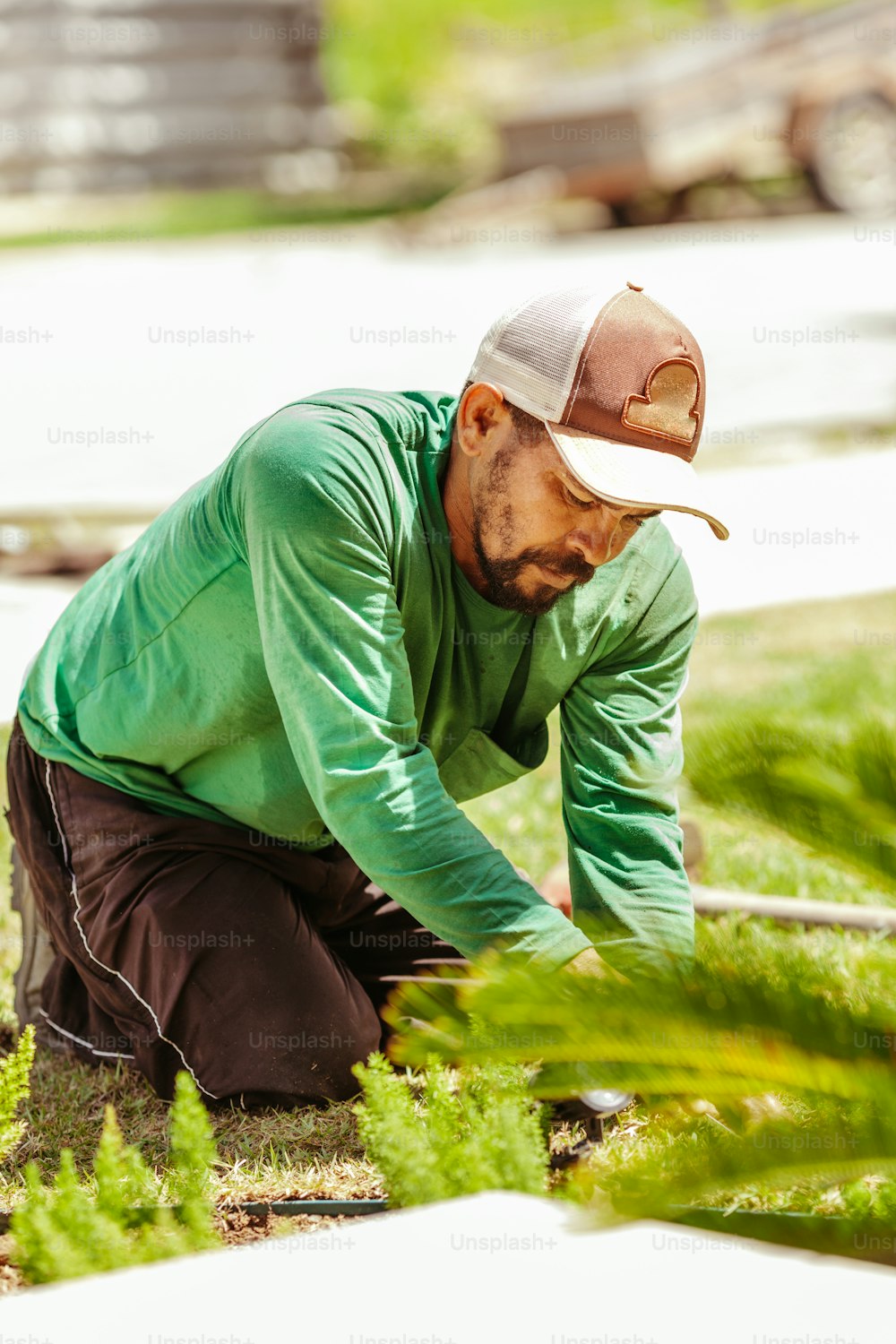 Un homme en chemise verte et chapeau travaillant dans un jardin