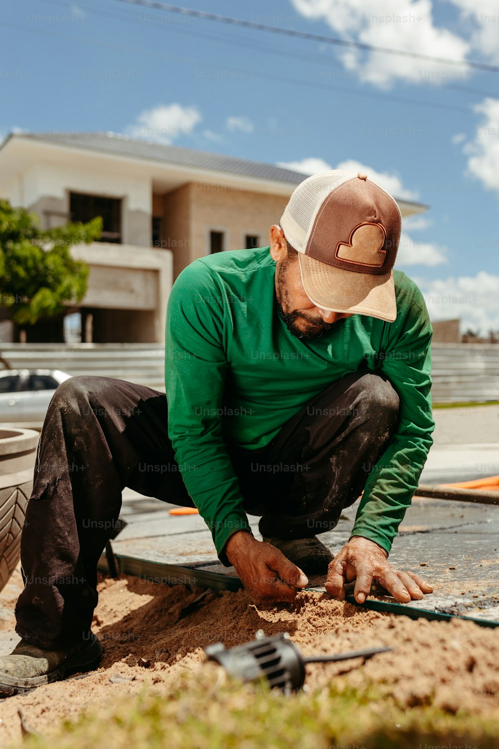 a man in a green shirt and hat working on a piece of wood