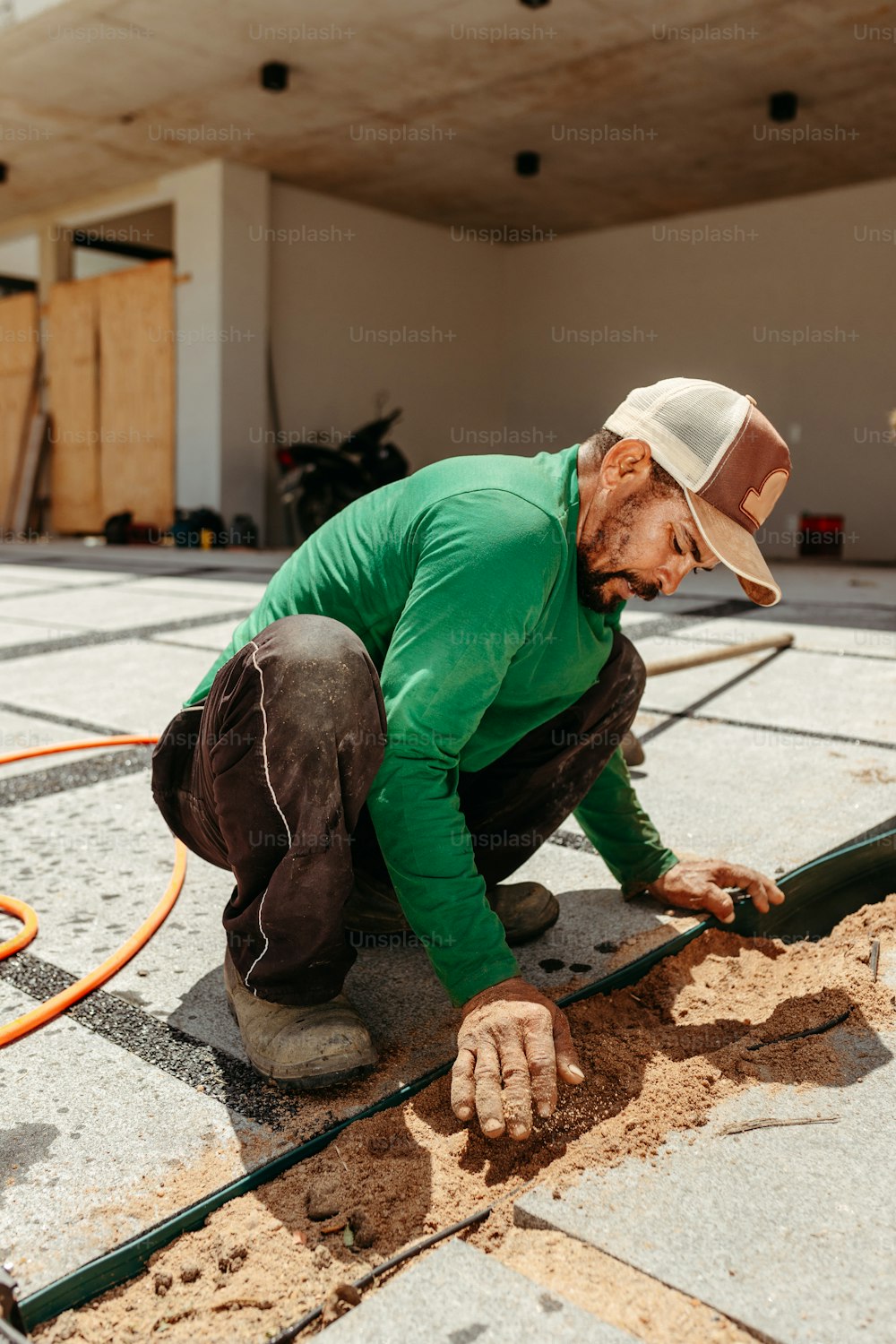 Un hombre trabajando en un piso con una manguera