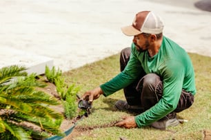 a man in a green shirt and hat is weeding a plant