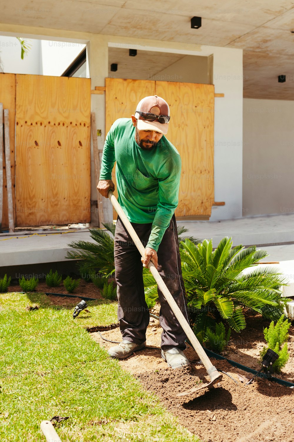 a man in a green shirt is using a shovel