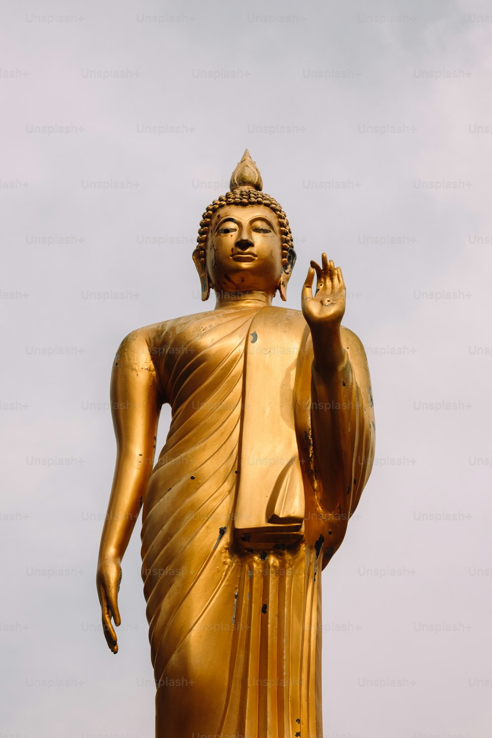 Una gran estatua dorada de Buda con un fondo de cielo