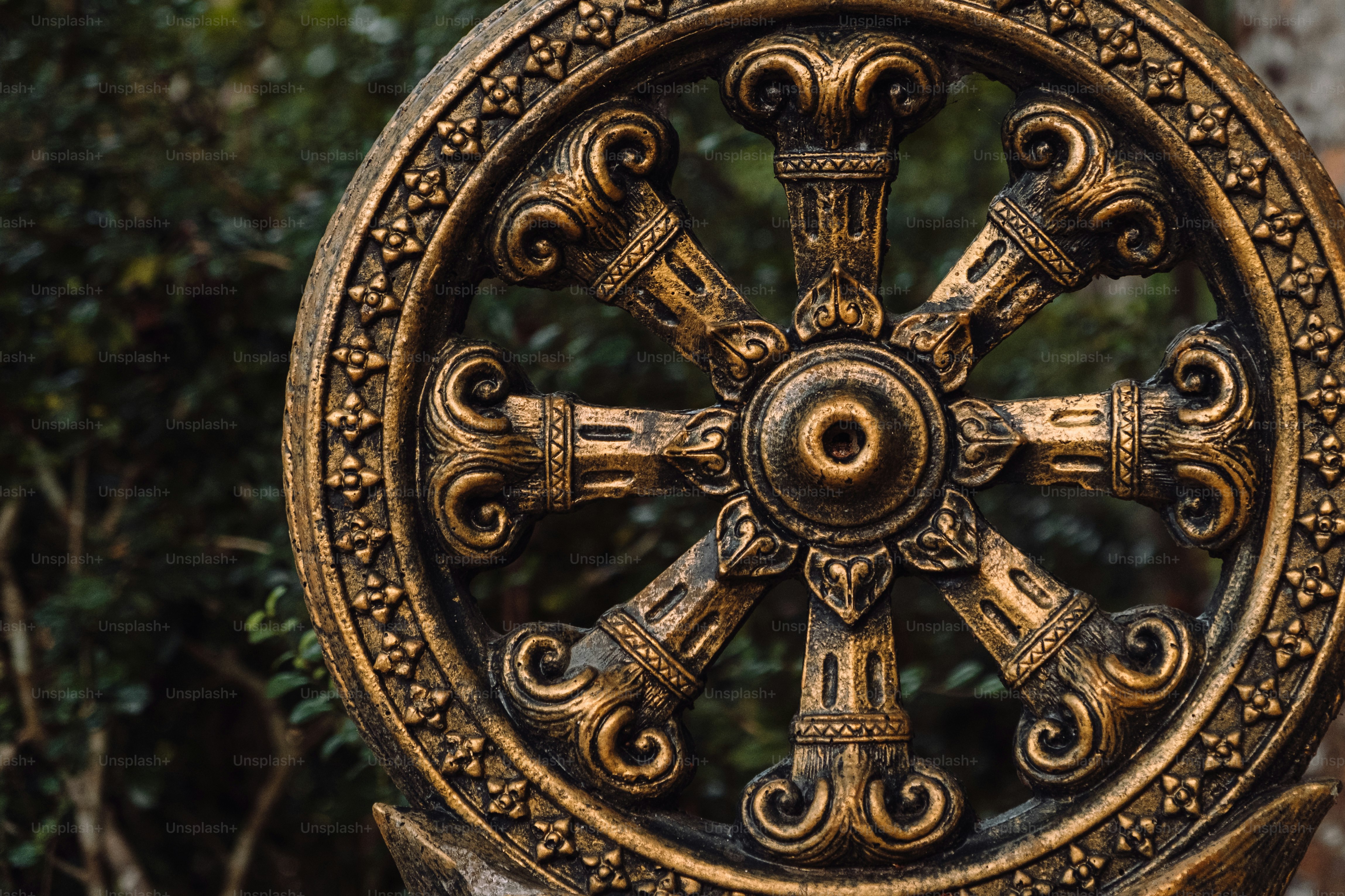 Eine goldene Statue eines Rades der Zeit vor einigen Bäumen