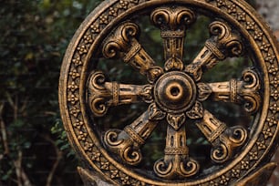 a golden statue of a wheel of time in front of some trees