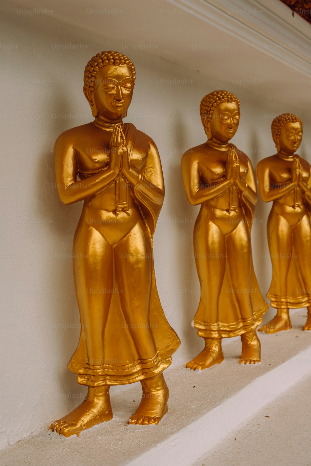 a row of golden buddha statues sitting on top of a shelf