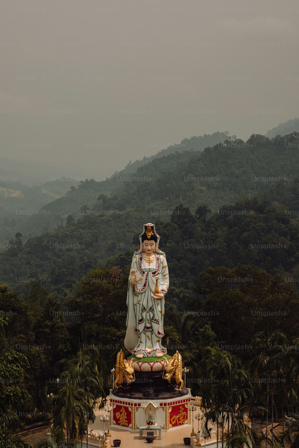 uma estátua de uma pessoa em pé no topo de uma colina