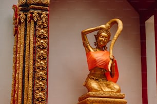 Eine goldene Statue einer Frau, die einen Stab hält