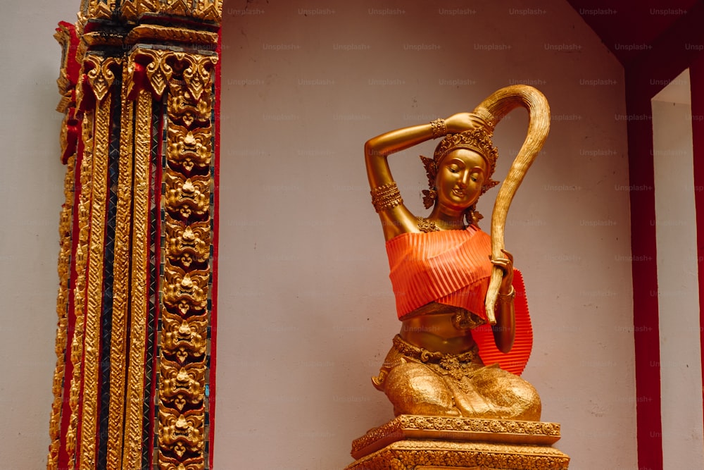 a gold statue of a woman holding a staff