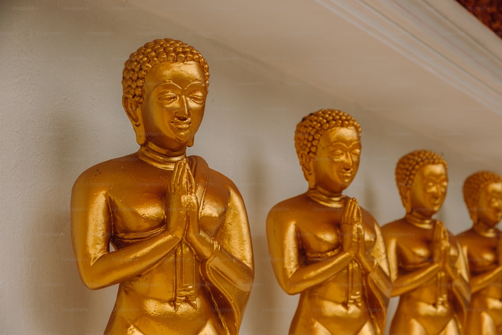Una fila di statue dorate di Buddha sedute l'una accanto all'altra