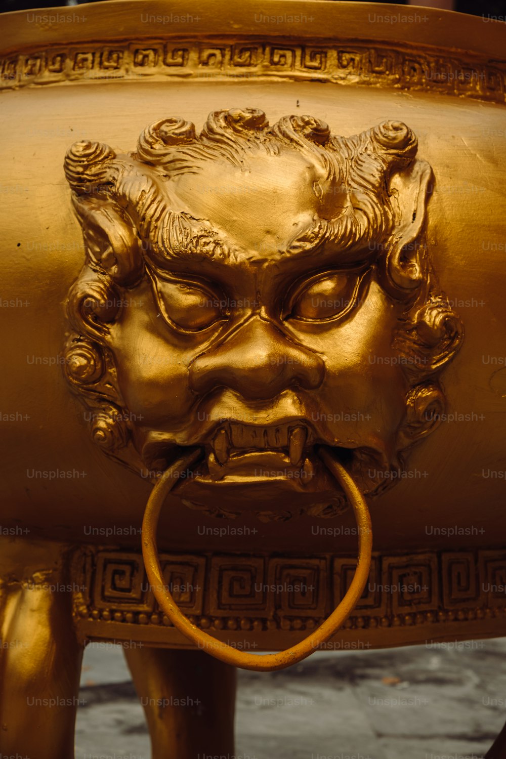 a golden statue of a lion with a ring in its mouth