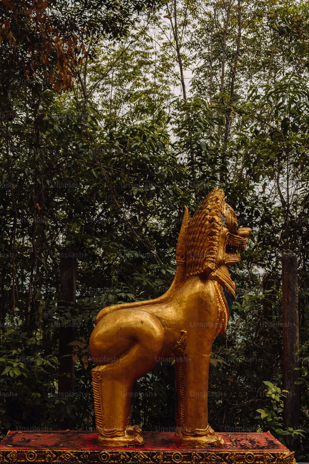 Una estatua de león dorado sentado encima de una caja roja