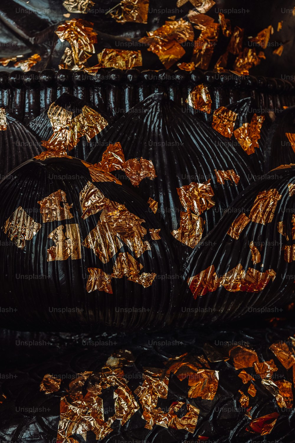 a pile of black and gold foil wrapped pumpkins
