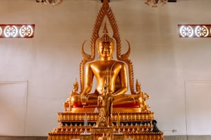 uma estátua dourada de Buda sentada em uma sala