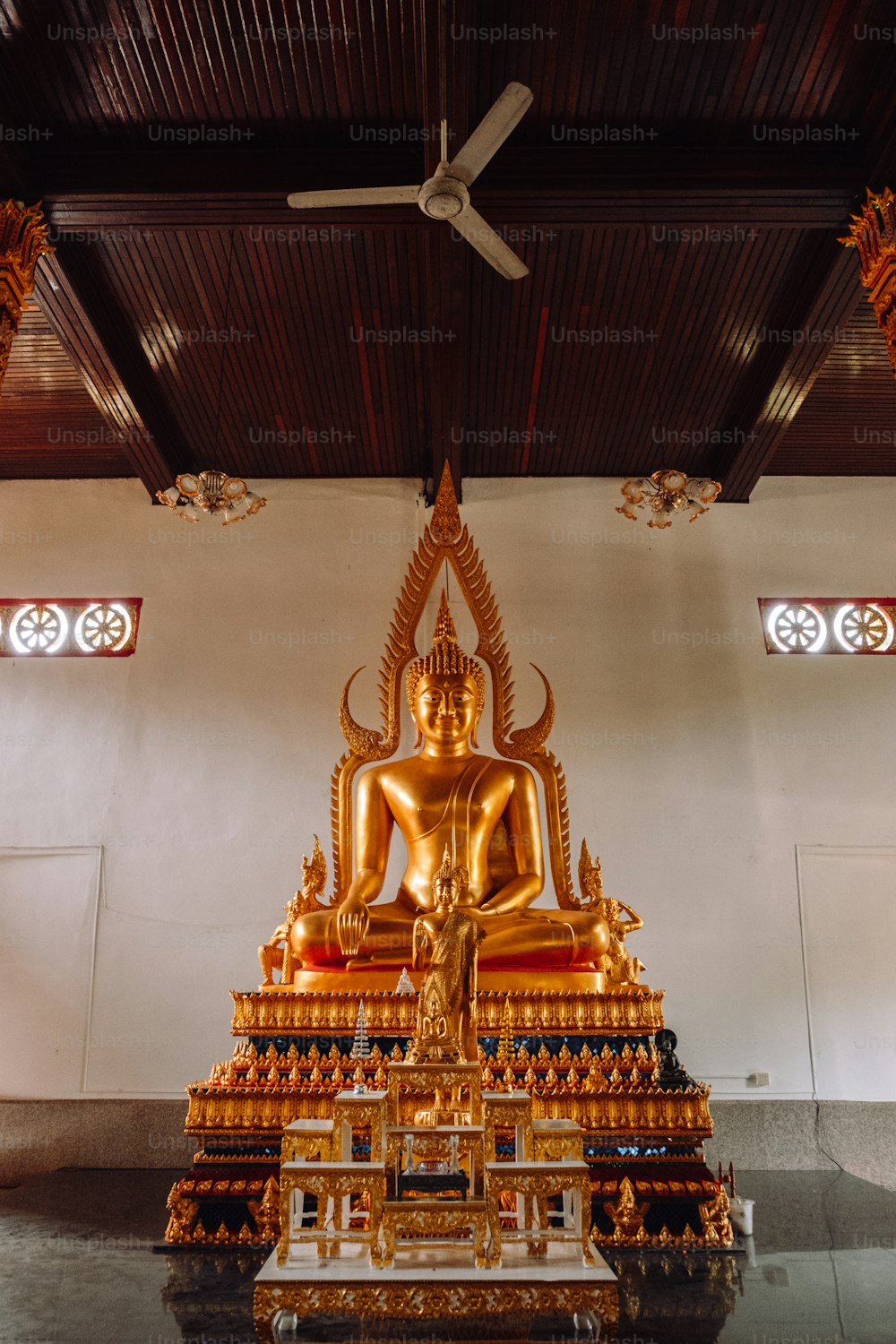 Une grande statue de Bouddha doré assise dans une pièce