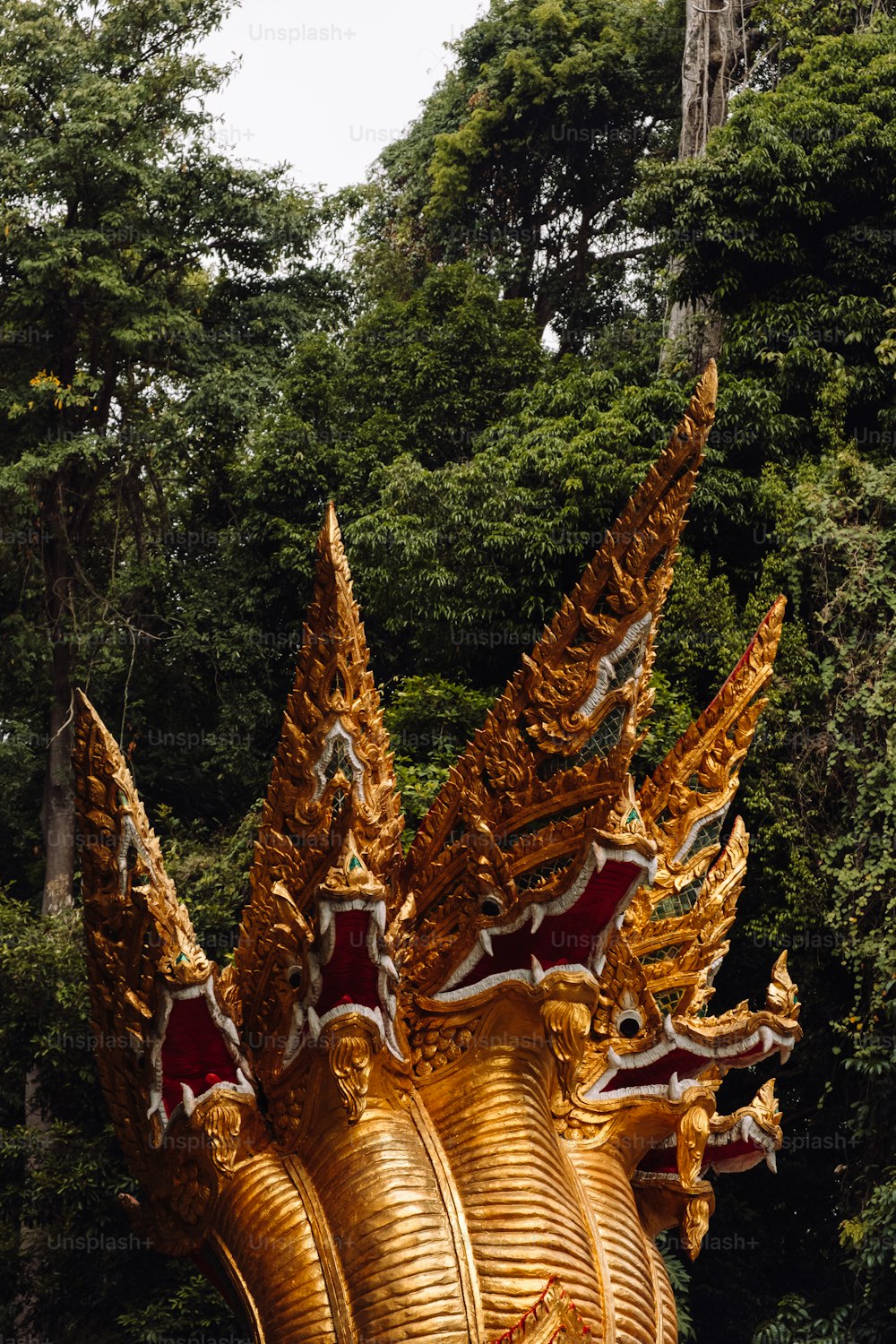Una gran estatua de dragón dorado frente a un bosque