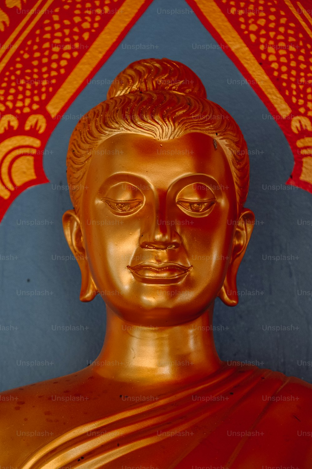 uma estátua dourada de Buda na frente de uma parede azul