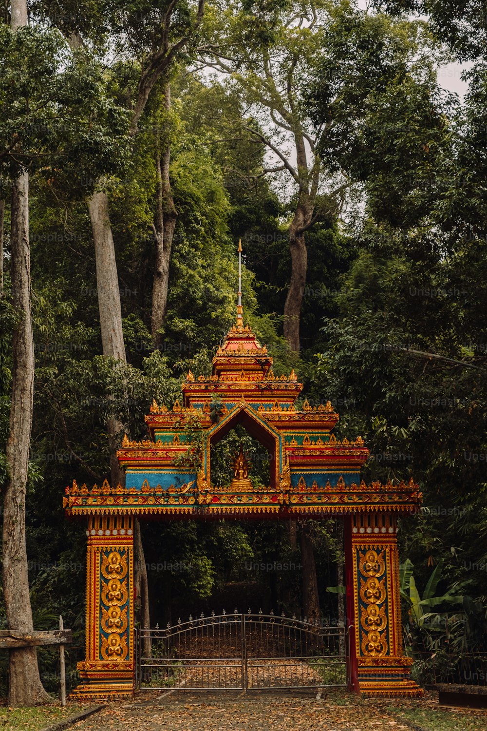 a colorful gate in the middle of a forest