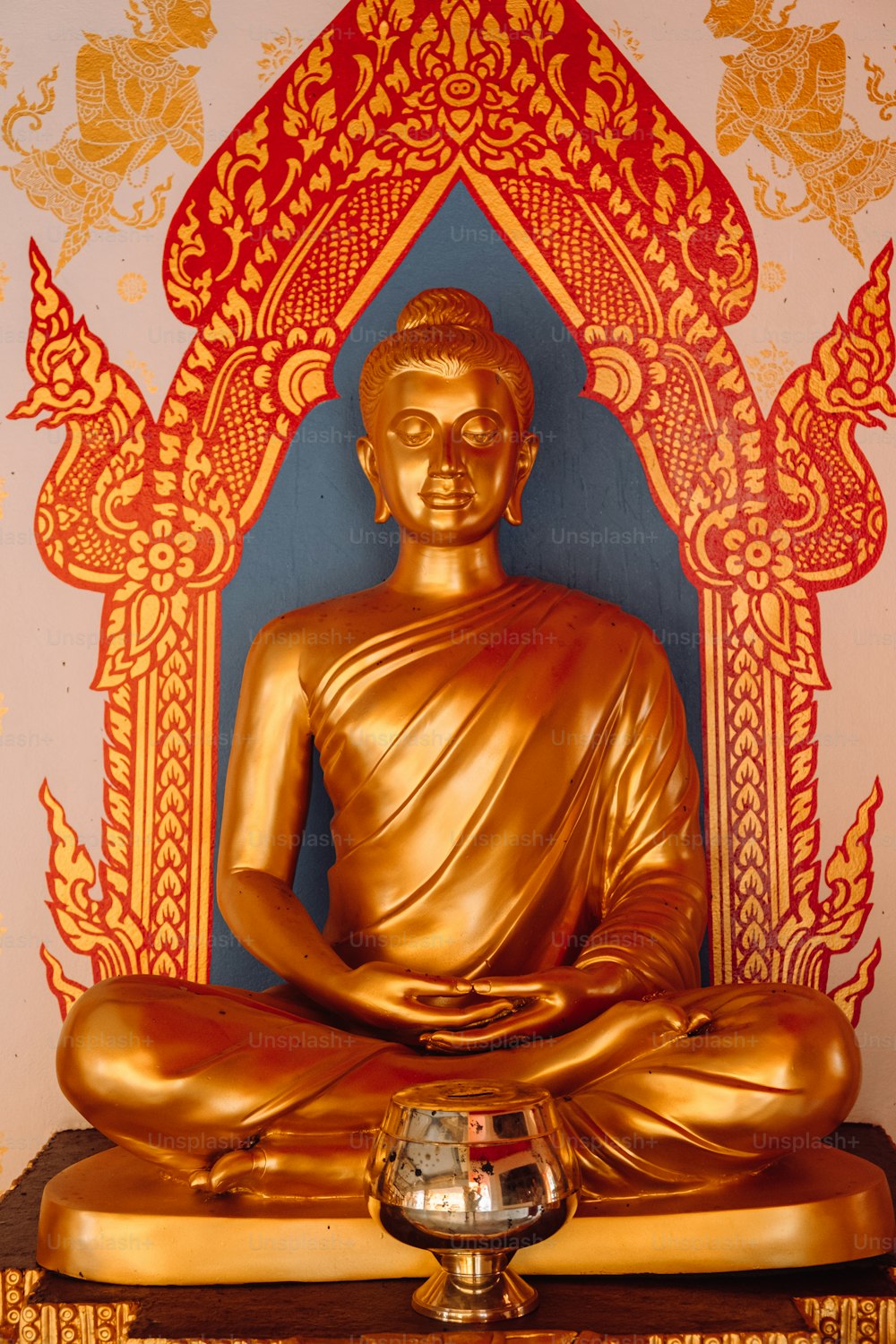 Eine goldene Buddha-Statue sitzt auf einem Holztisch