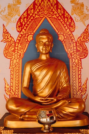 a golden buddha statue sitting on top of a wooden table