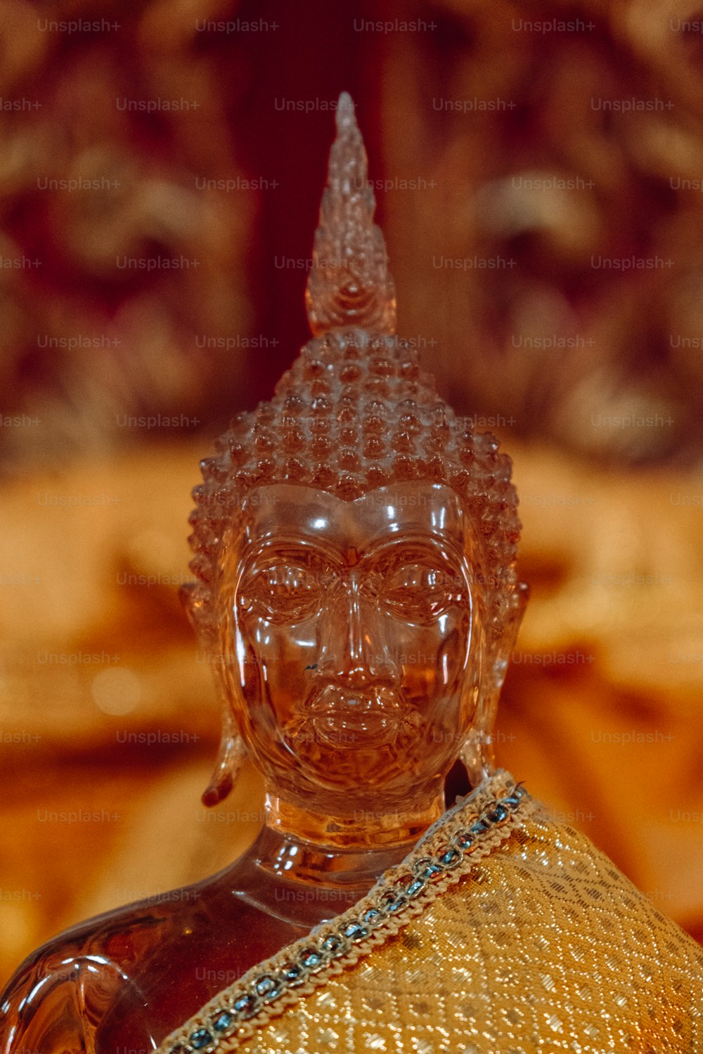 uma estátua de vidro de buddha sentada em cima de uma mesa
