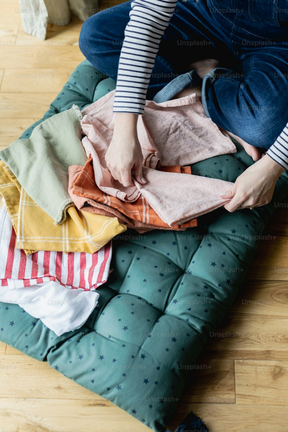 a woman sitting on a mattress with clothes on it