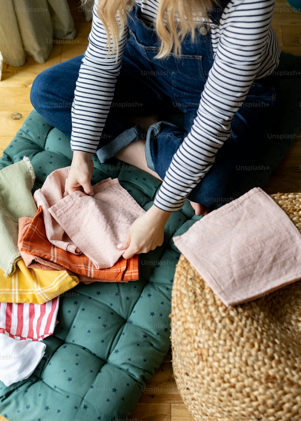 a woman sitting on the floor next to a pile of clothes