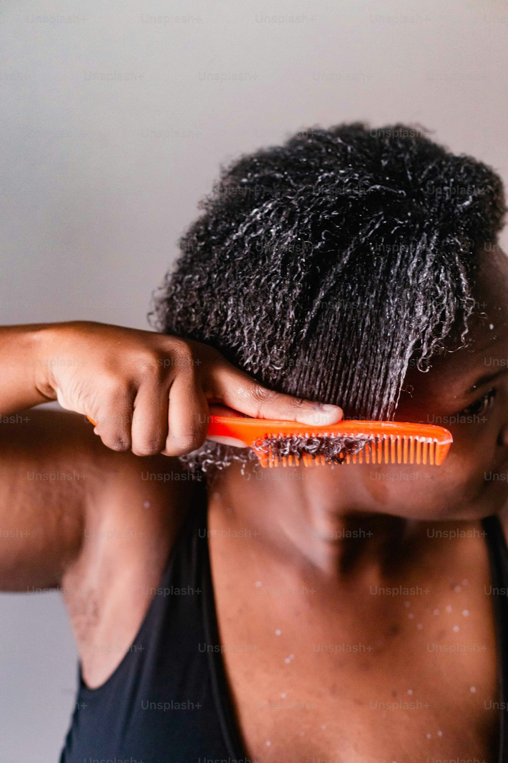 um homem está escovando o cabelo com um pente laranja