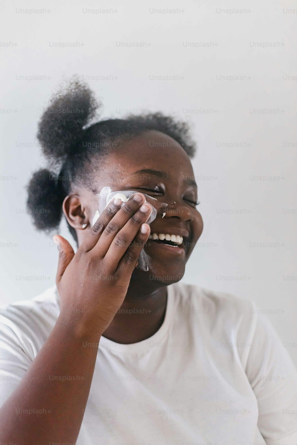 a woman smiles as she wipes her face with a cloth