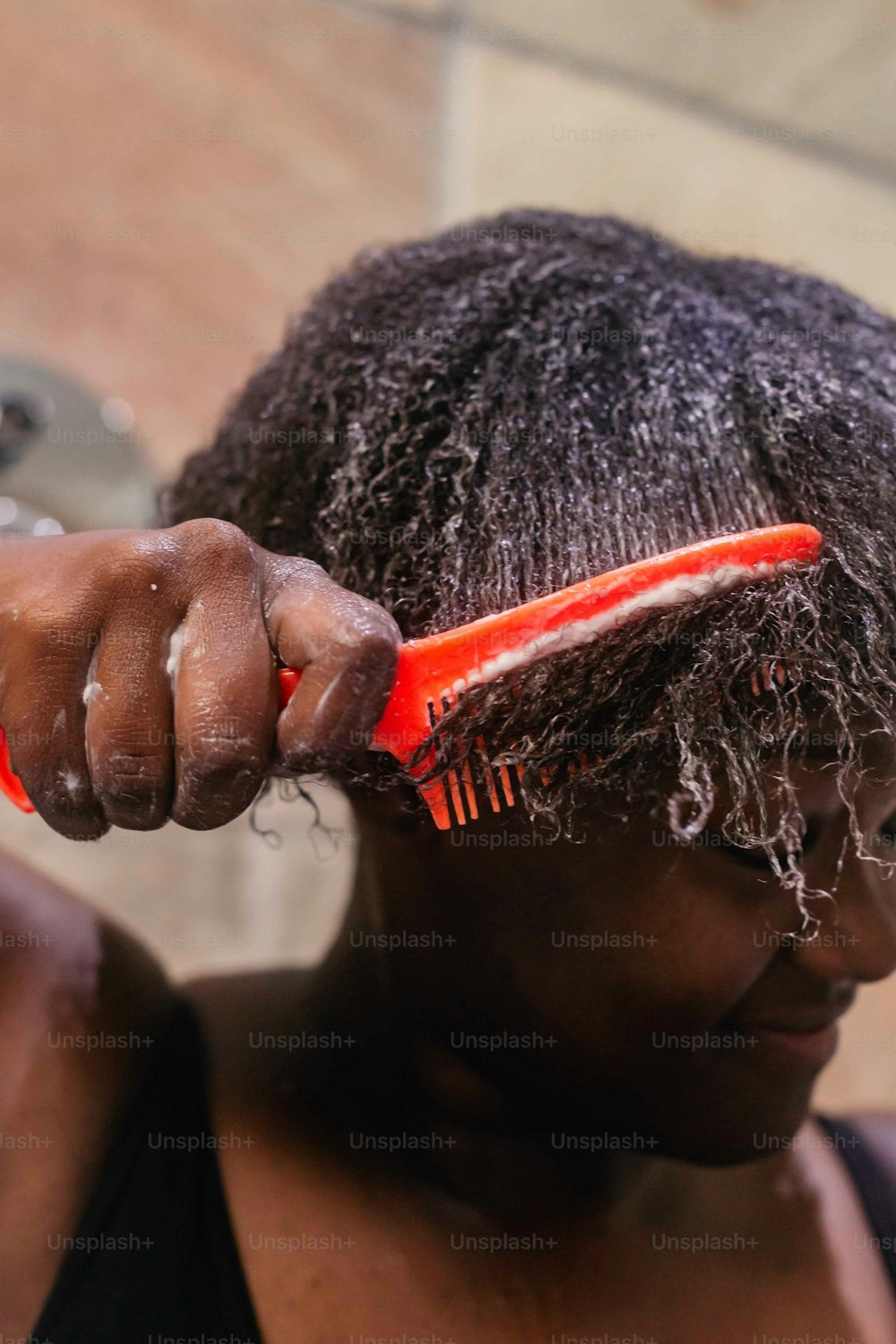 uma mulher está escovando o cabelo com um pente vermelho