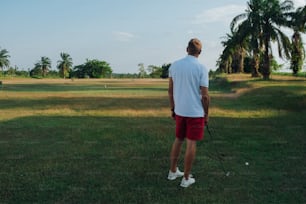 Un hombre con camisa blanca y pantalones cortos rojos jugando al golf