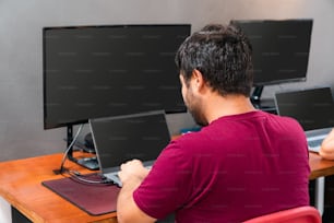 机に座ってコンピューターで作業している男性