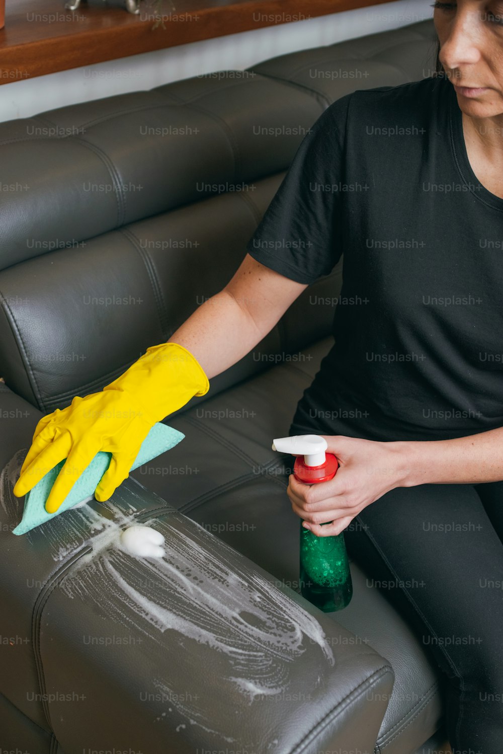 a woman cleaning a couch with a yellow glove