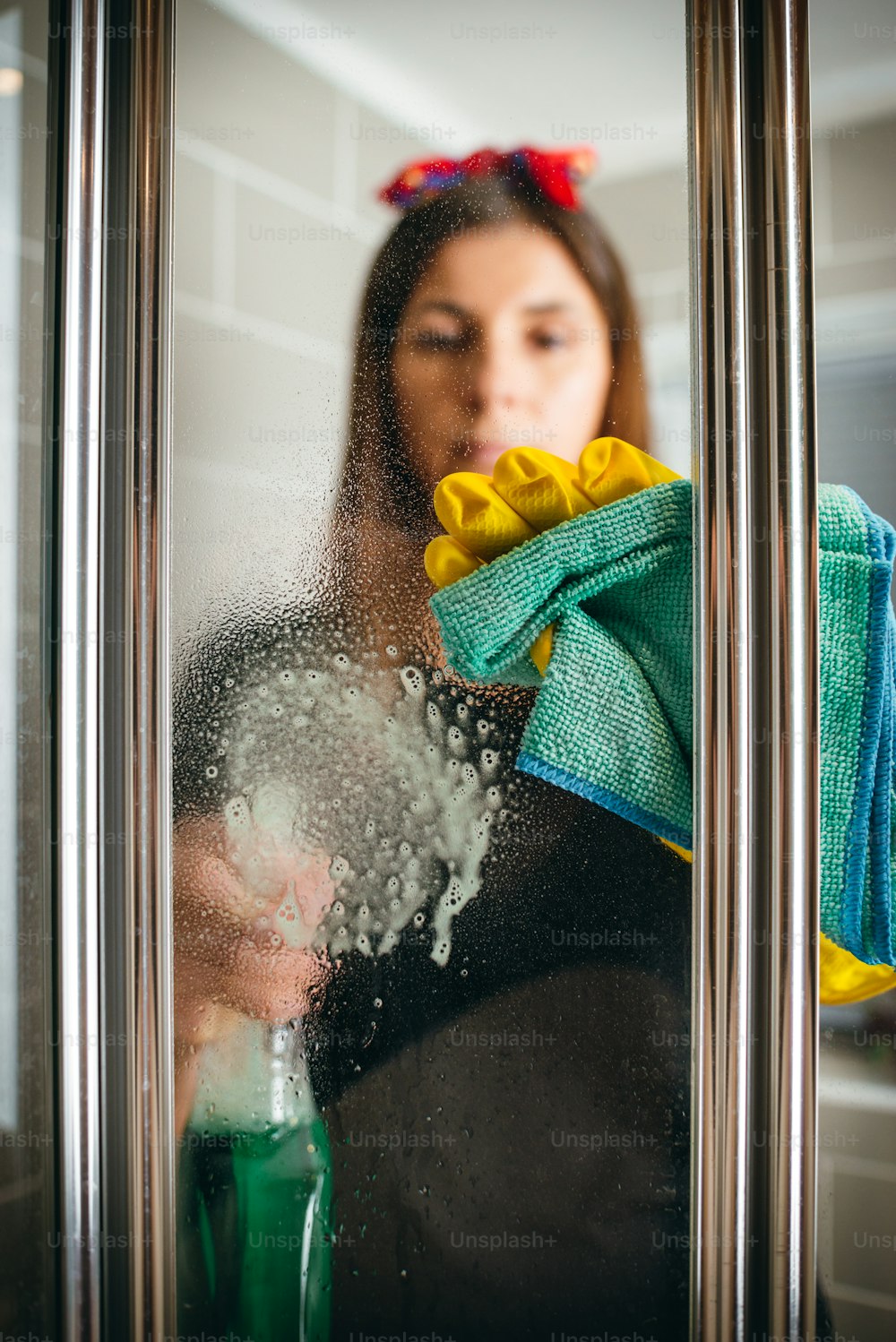 a woman cleaning a glass door with a rag