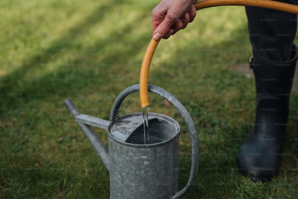 a person holding a hose and a watering can
