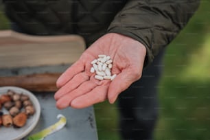 a person holding a handful of white pills in their hand