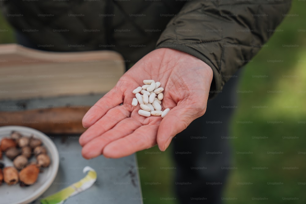 a person holding a handful of white pills in their hand