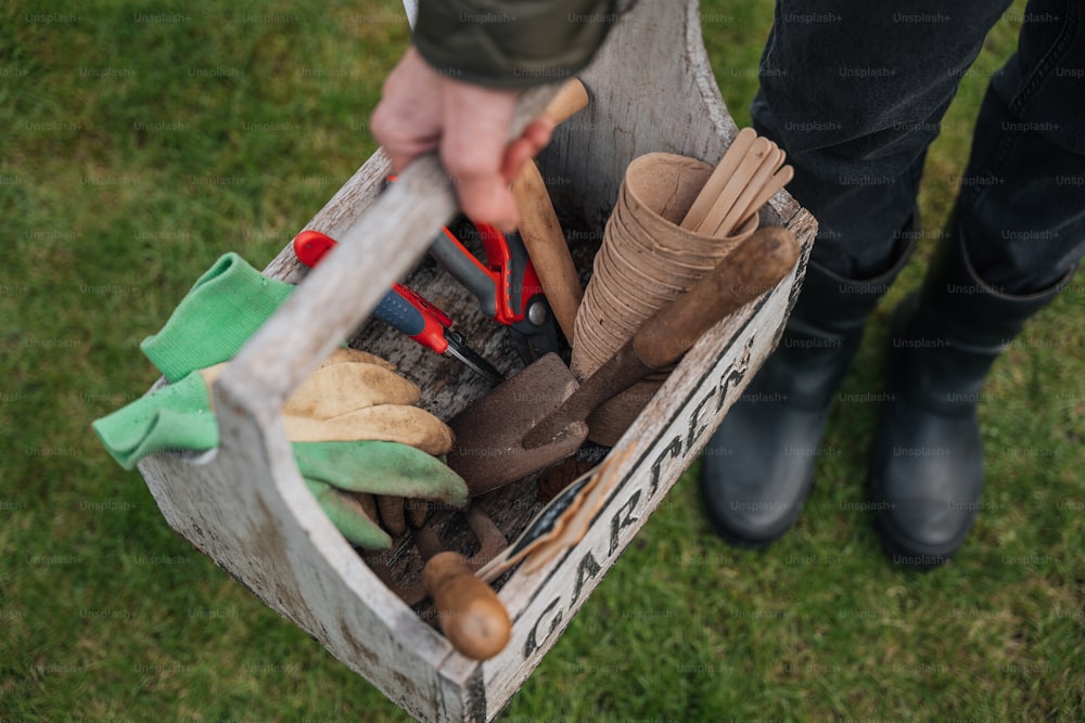 a person holding a box full of gardening tools