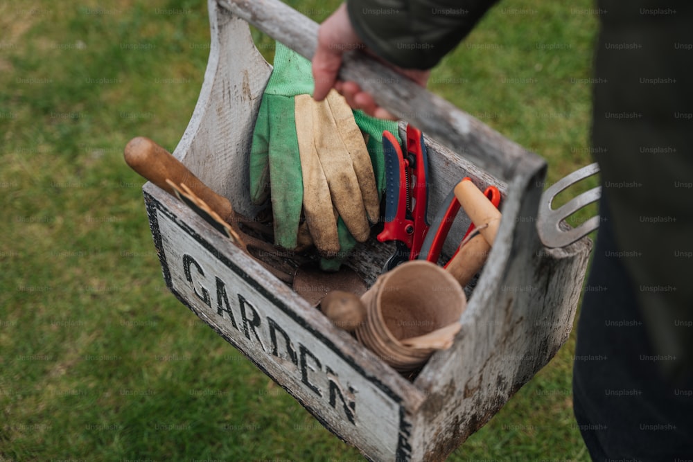 a person holding a wooden box filled with gardening tools