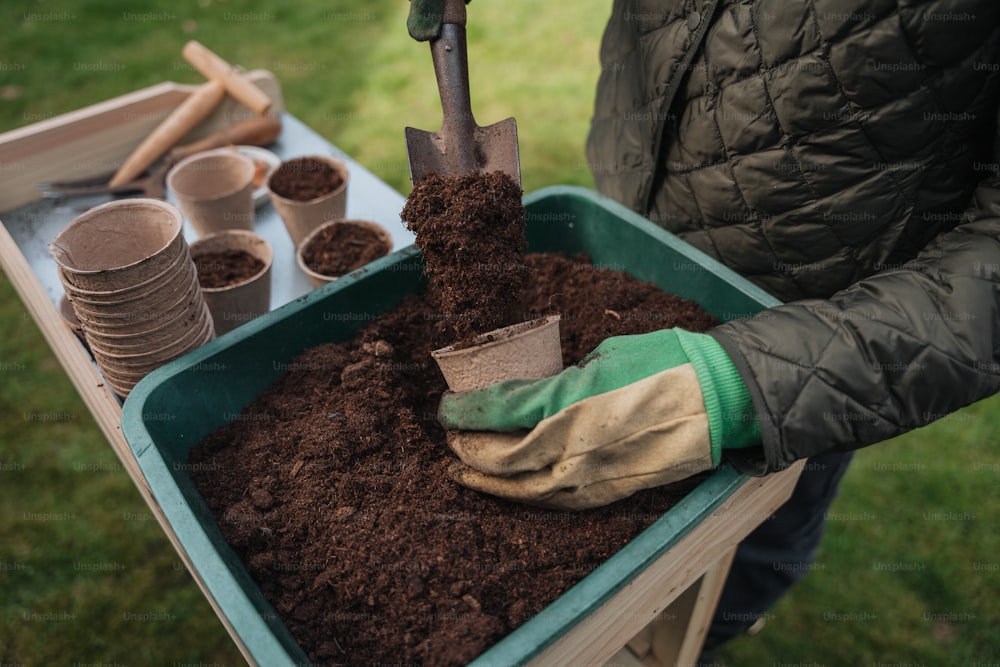 a person holding a shovel in a tray of dirt