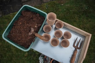 una bandeja de tierra y utensilios de jardinería sobre una mesa