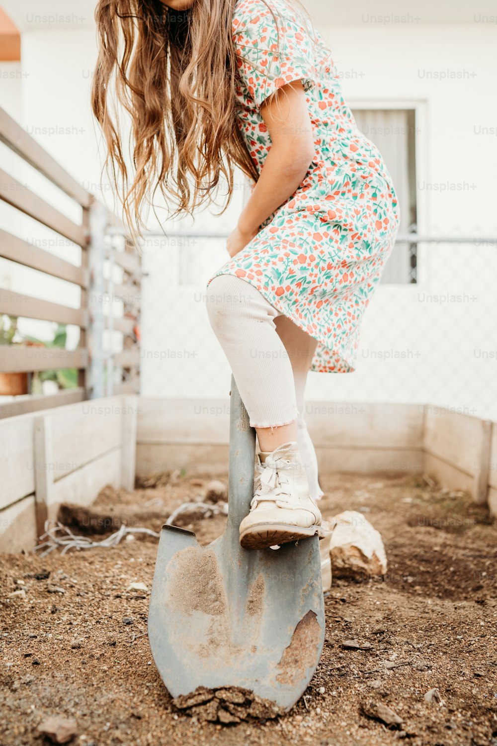 a young girl riding on top of a metal shovel