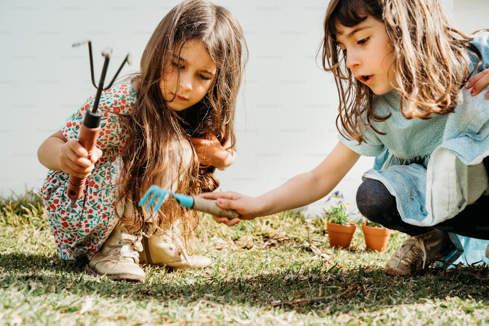 two little girls are playing with gardening utensils